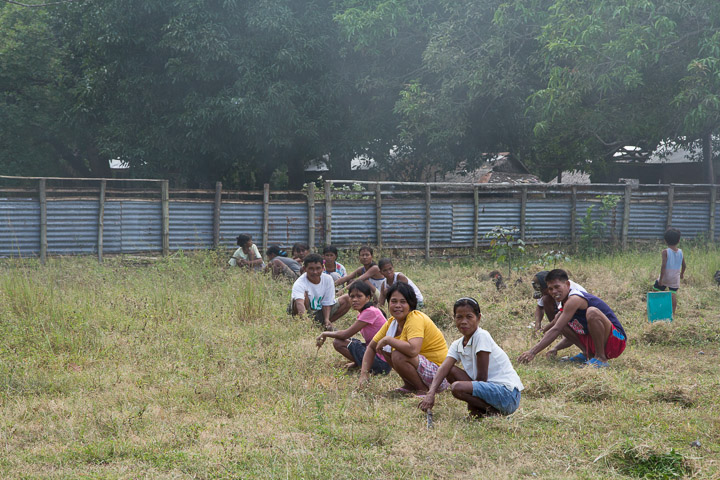 Parents d'élèves Tagbanua coupant l'herbe de la cour de l'école, Philippines © Camille Oger